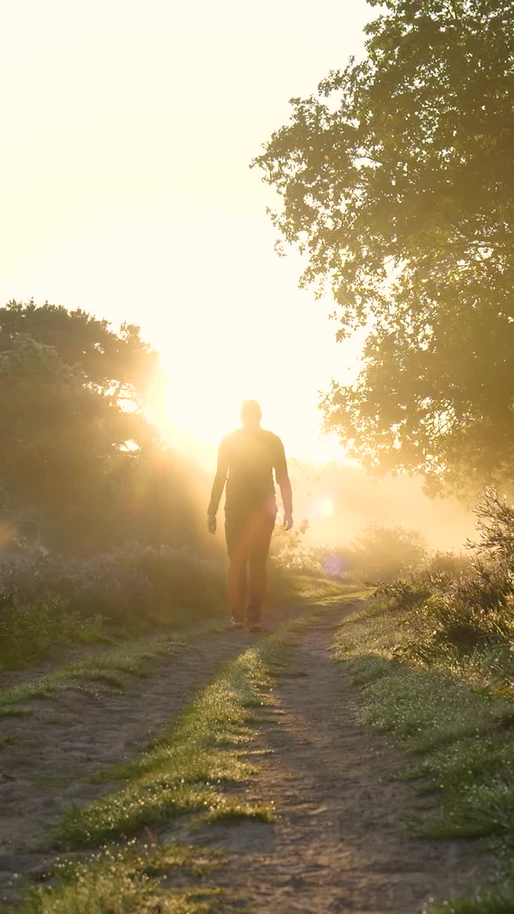 hombre caminando por un camino al amanecer