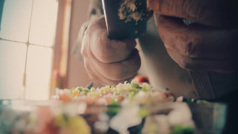 hands close up using a knife to cut garlic in very small pieces to add it to the salad