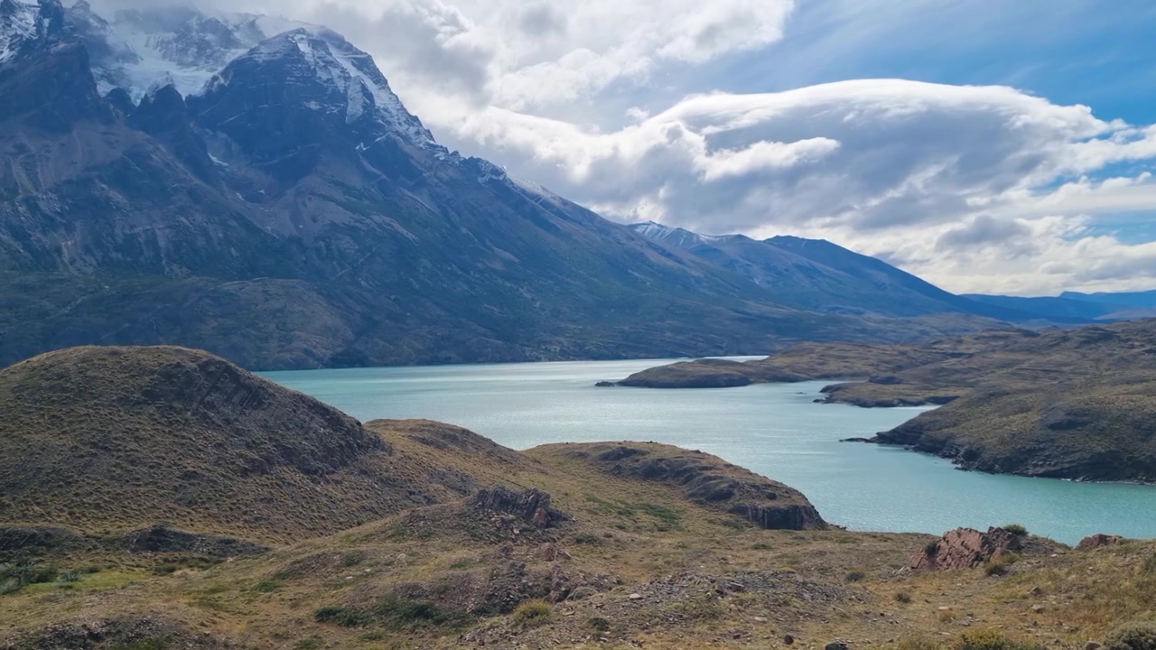 Splendida natura selvaggia della Patagonia nel Parco Nazionale Torres del Paine, Cile. Cime aspre si ergono sopra il lago turchese Pehoé sotto nuvole drammatiche, mostrando una bellezza naturale incontaminata.