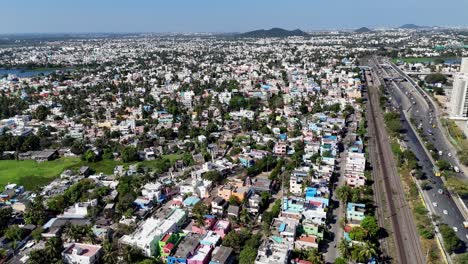 expansive aerial drone shot showcasing a vast and colorful residential cityscape in chennai, with a glimpse of an urban lake and distant infrastructure under a clear sky.