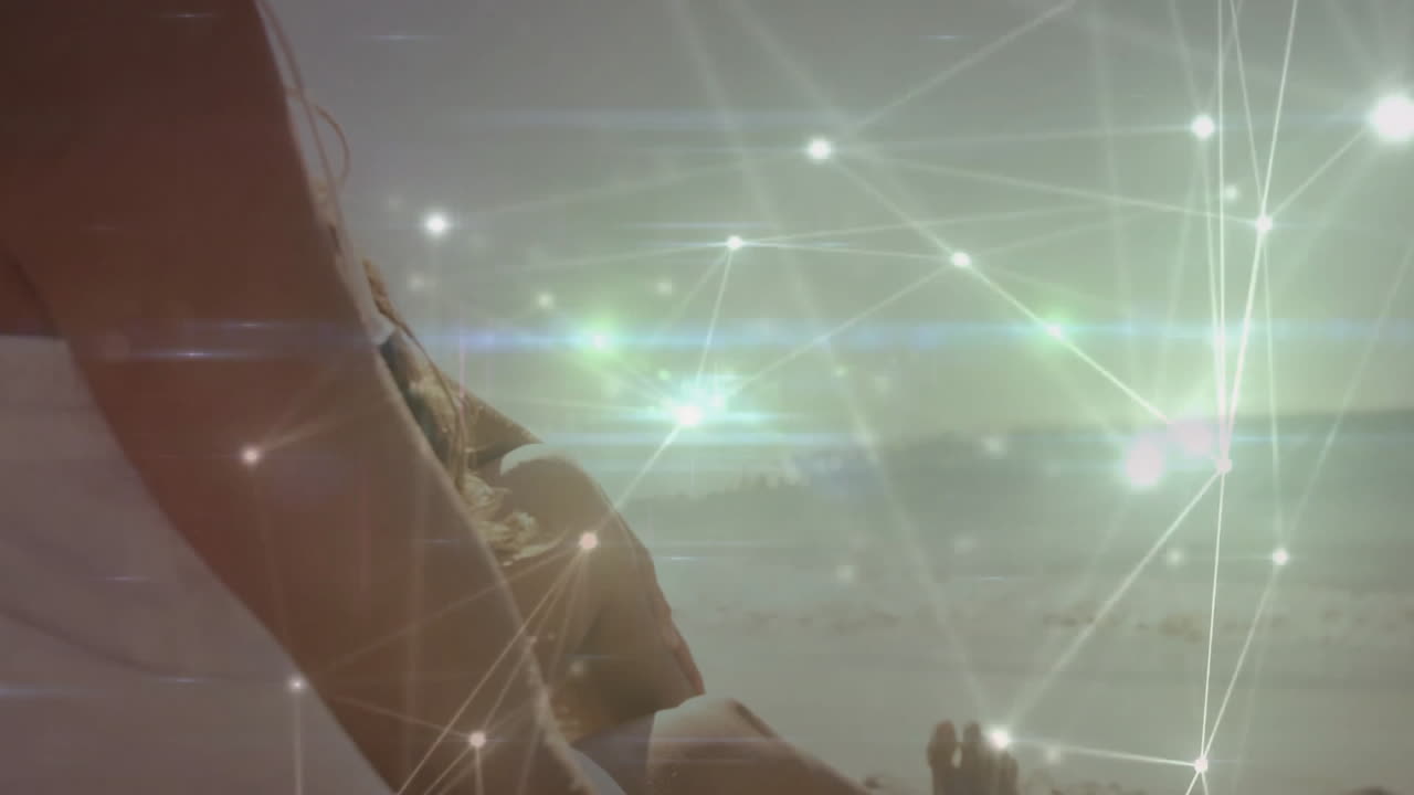 Animation of glowing network connections over person standing by ocean