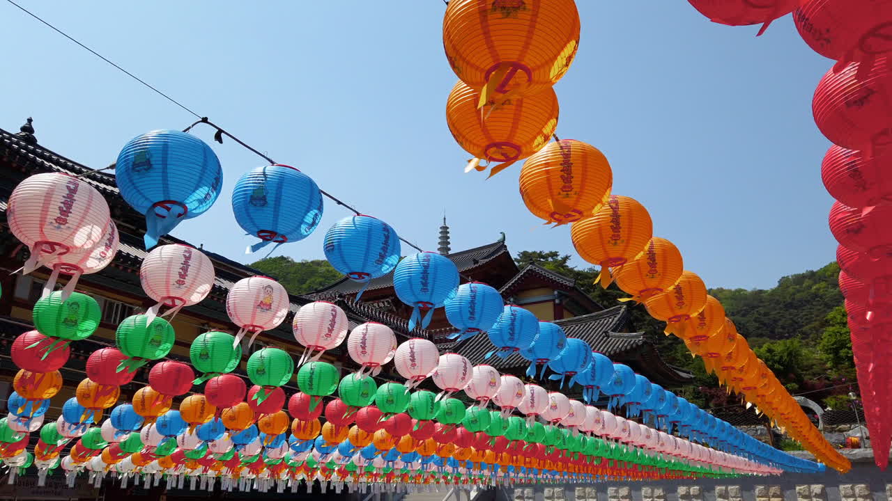 Colorful lanterns swaying in breeze at Buddhist temple with pagoda in background.  Hopyeong Namyangju South Korea.