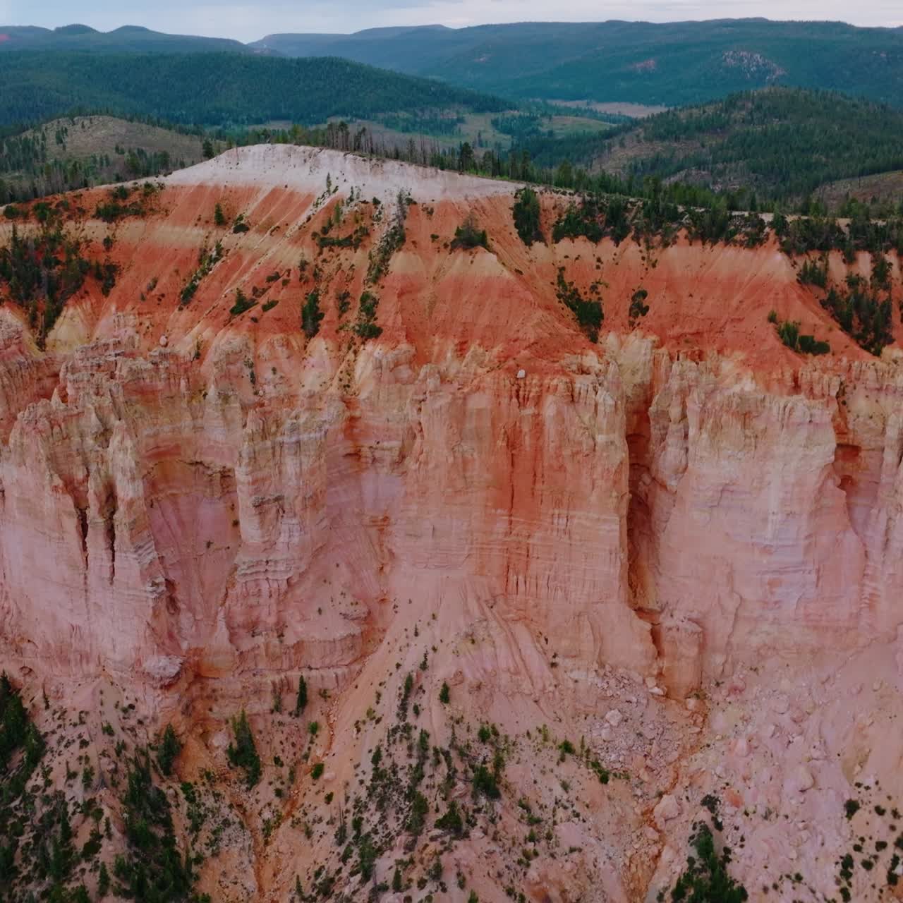 Stunning huge rock of coral color in Bryce National Park. Mountains overgrown with pine forest at backdrop. Aerial view