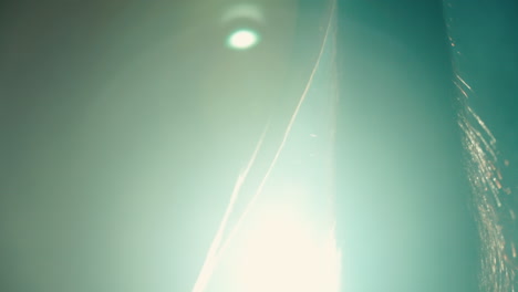 closeup of brown horse tail slowly swaying against teal atmospheric haze, lens flare