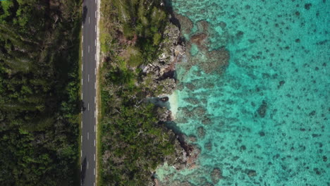 Vista-Panorámica-De-La-Carretera-Del-Desierto-A-Lo-Largo-De-La-Costa-Escarpada,-Agua-Cristalina-En-Las-Islas-De-Lealtad,-Nueva-Caledonia