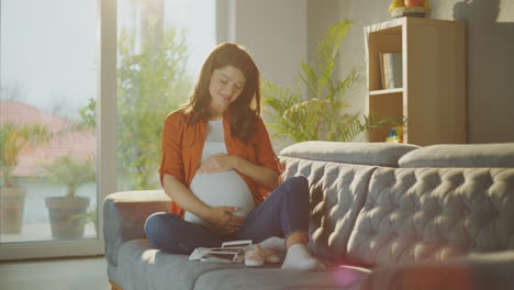 pregnant woman on sofa with baby shoes