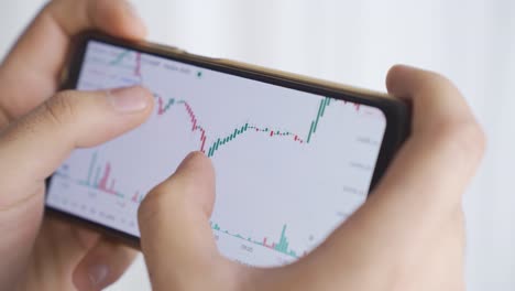 Close-up-of-man-looking-at-stock-market,-stock,-investment-charts-on-phone.