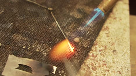 melting metal wires with butane gas flame burner - close up shot in slow motion