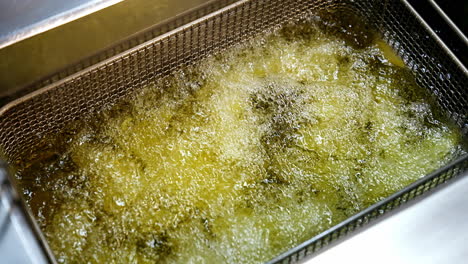 french fries in the deep fryer. fast food restaurant, cooking potato, crispy fries. junk food concept. top view video. close up.