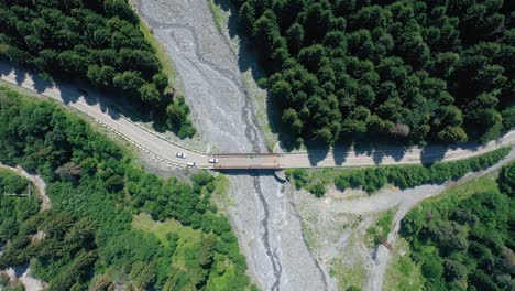 Cars-Crossing-On-The-Bridge-In-Shovi,-Region-Of-Racha-In-Georgia-On-A-Sunny-Day---top-down-aerial-shot