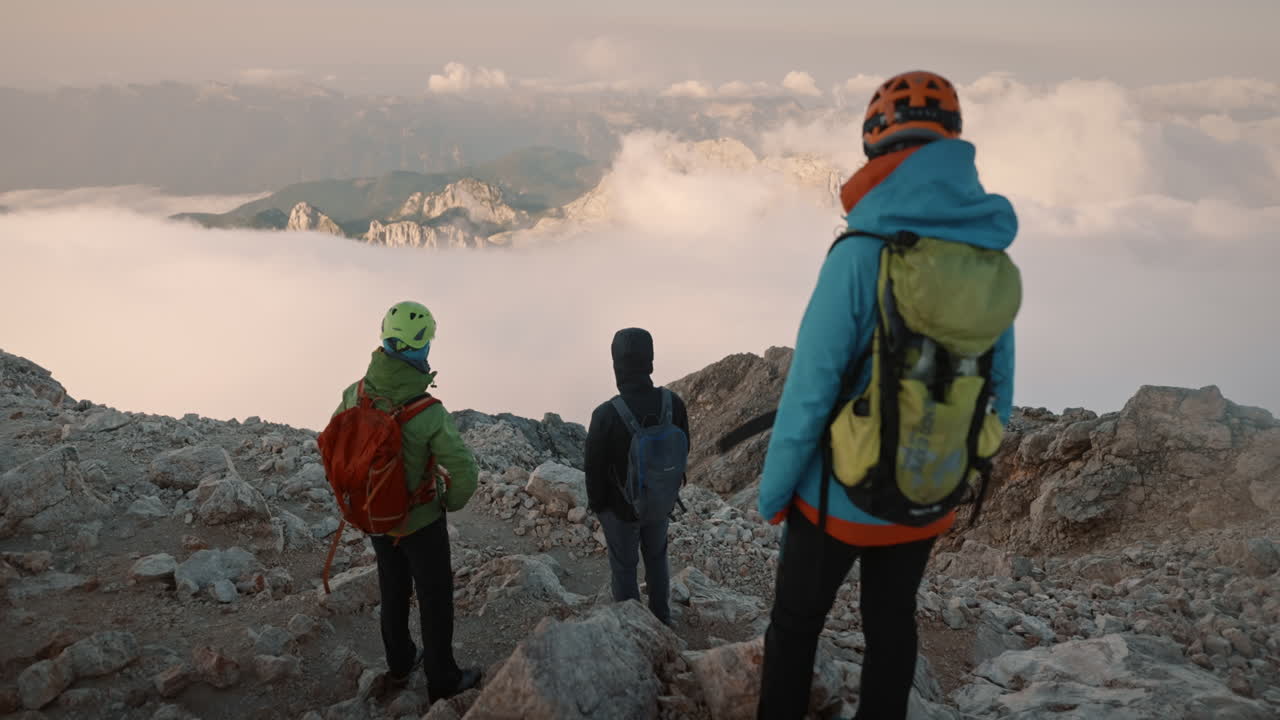 excursionistas de pie sobre grandes rocas en su equipo de escalada mirando hacia el valle temprano en la mañana en el paso de couds