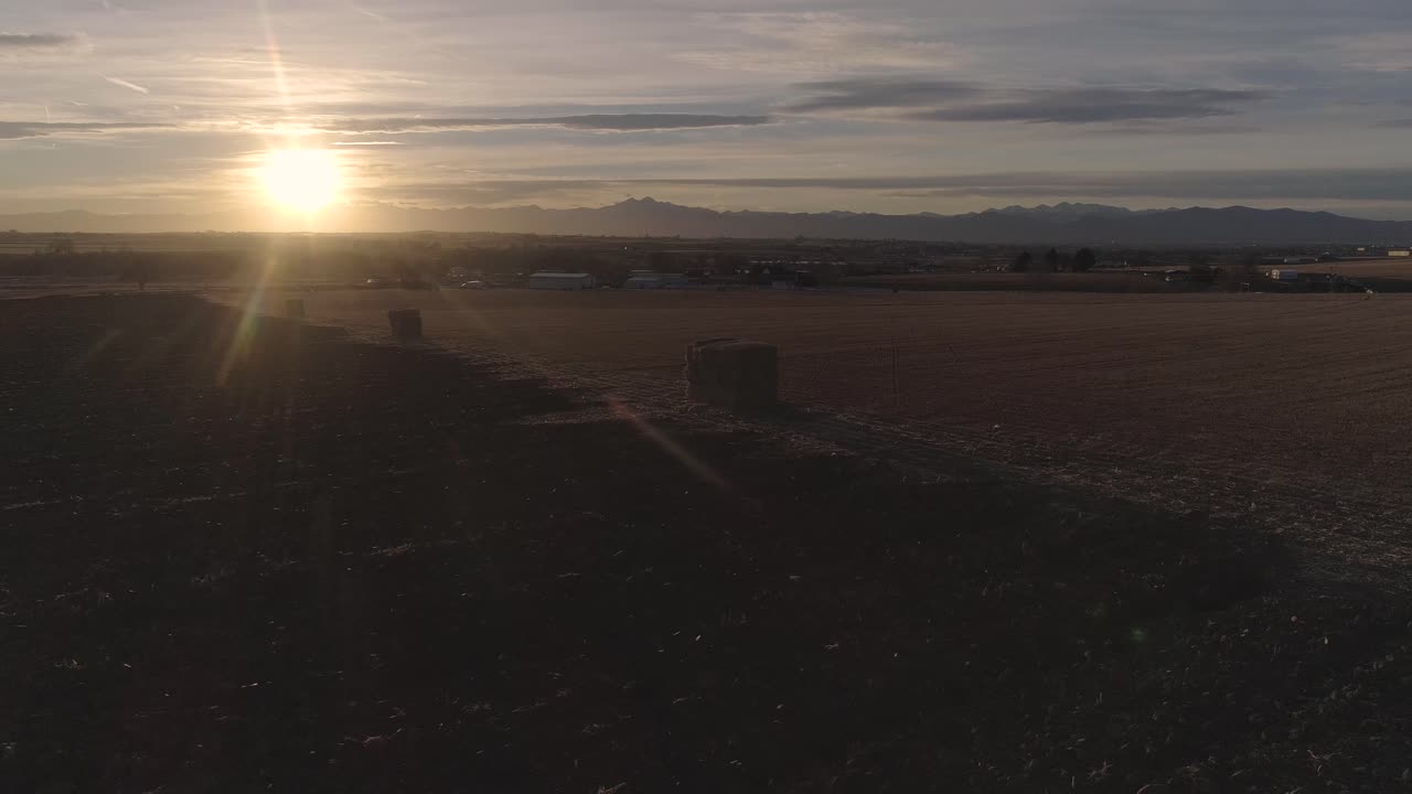 fianzas de heno de colorado durante la puesta de sol contra las montañas rocosas