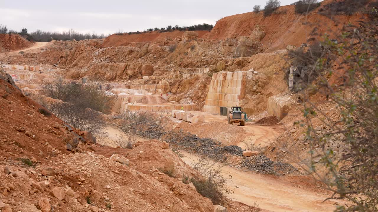 Limestone quarry with loader excavator carrying stone debris, Wide handheld shot