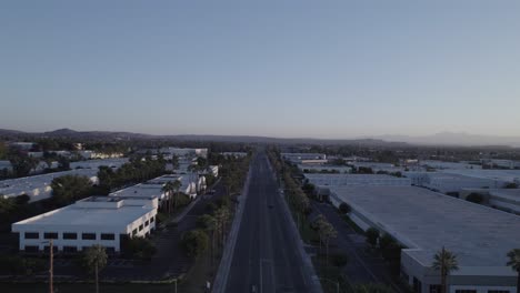 A-drone-takes-flight,-gracefully-gliding-over-a-commercial-street-with-the-buildings-bathed-in-the-soft,-warm-hues-of-the-evening-sky-just-before-sunset