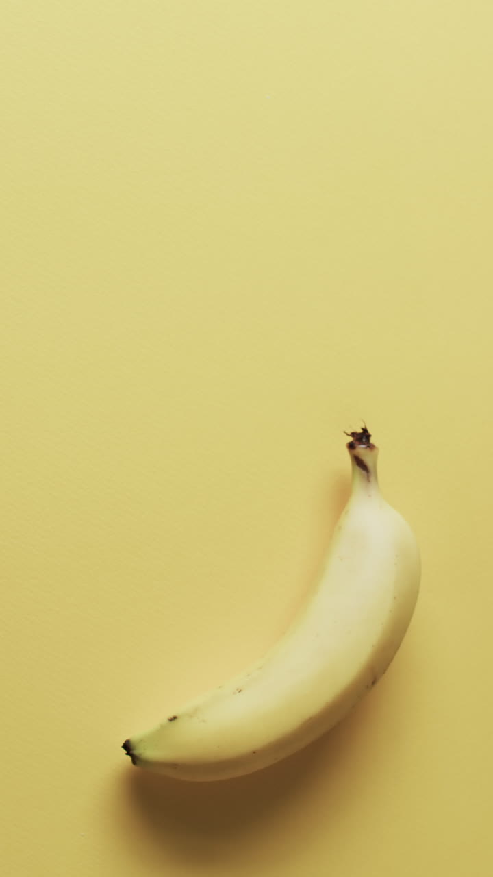 Vertical video of banana with copy space over yellow background
