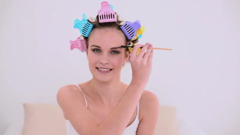 joven modelo con rodillos de cabello cepillándose las cejas