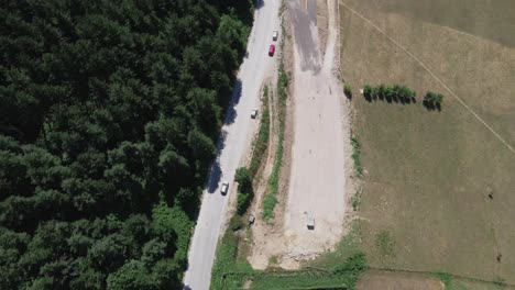 car driving along narrow street mountain road in countryside with plowed land and wild green forest woodland vegetation