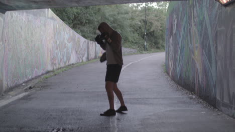 Young-Active-Man-Boxing-In-Underpass,-Silhouetted-By-Light