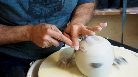 master potter trimming with a tool on the wheel