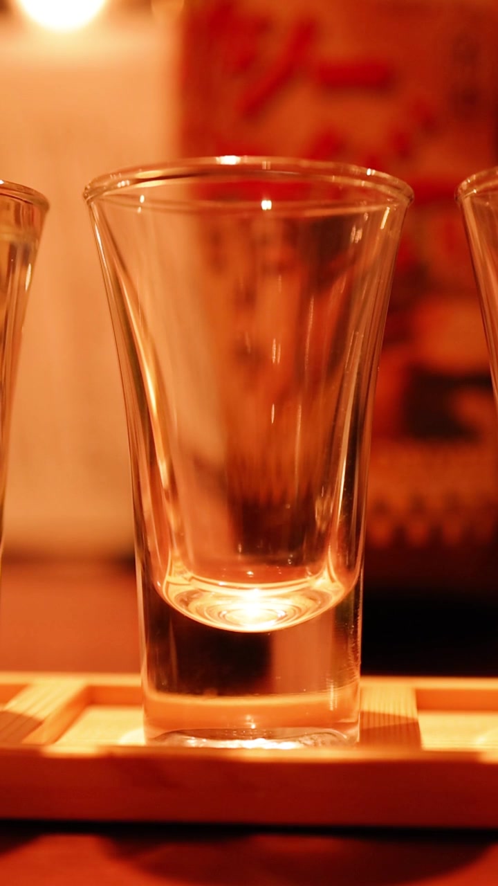 Bicchieri da sake che vengono riempiti su un supporto di legno