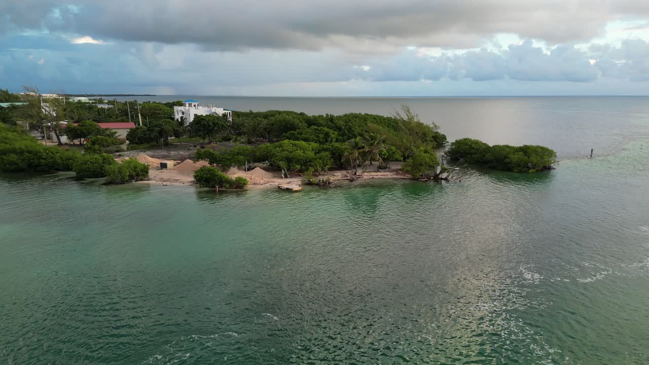 vista de avión no tripulado en belice volando sobre un pequeño barco cruzando un canal entre dos cayos en el mar del caribe en un día nublado