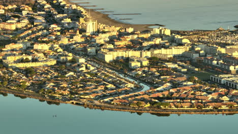 Palavas-les-Flots-skyline-bathed-in-golden-light,-coast-in-the-backdrop.