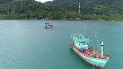 Drone-shot-of-a-sinking-fishing-boat-that-are-being-towed-by-another-boat