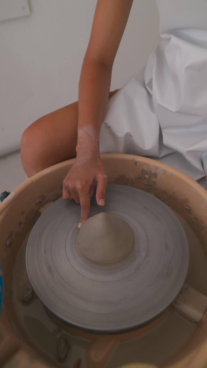 Person working on a pottery wheel shaping clay