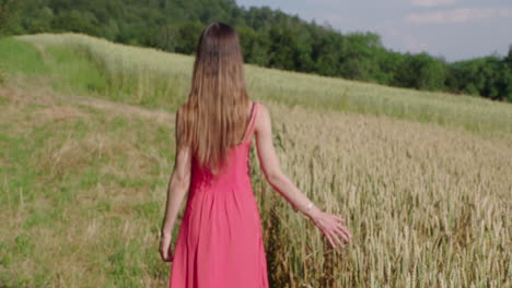 a-woman-in-a-red-dress-is-walking-along-a-grain-field