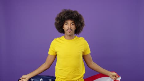 happy man with afro holding an american flag against a purple background