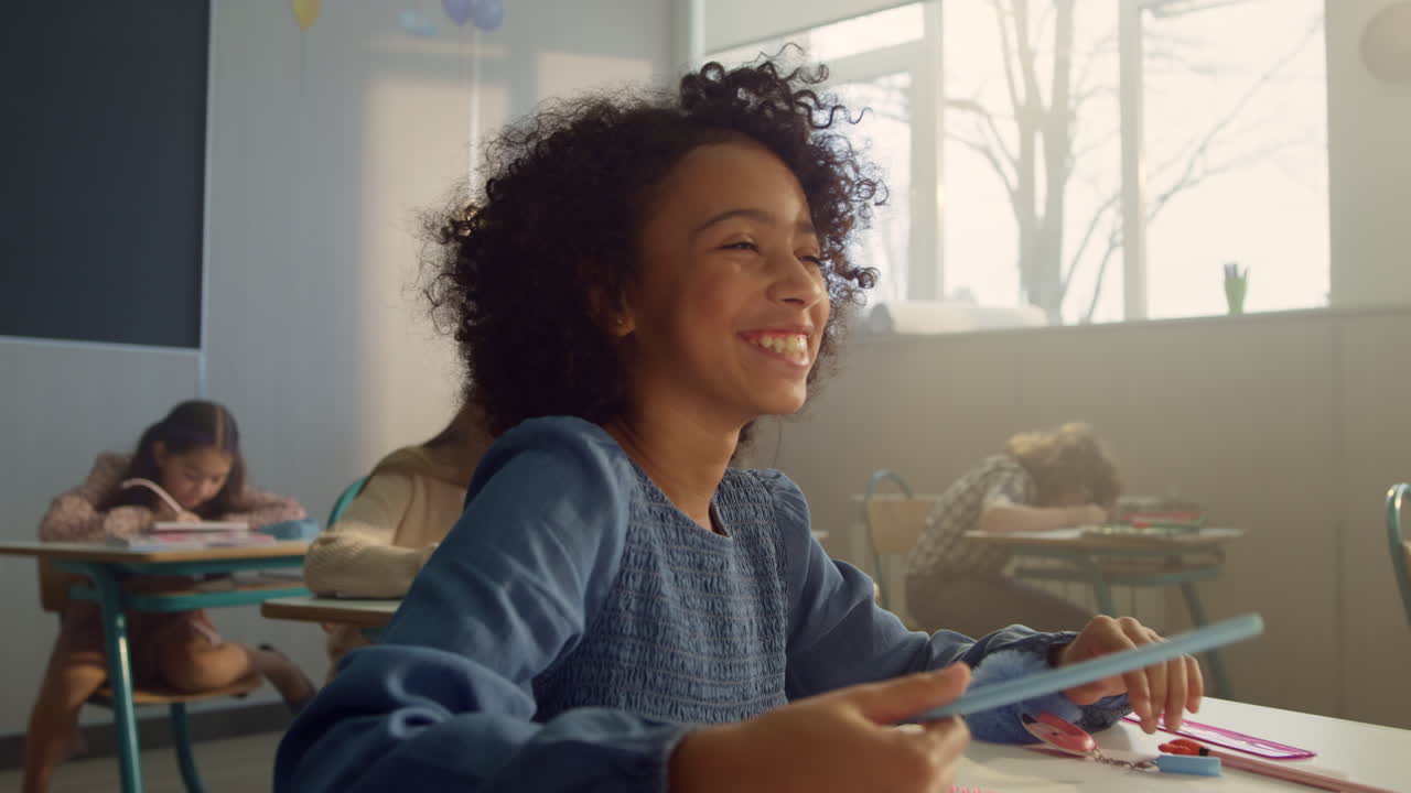 Smiling student raising hand at lesson. Laughing schoolgirl answering question