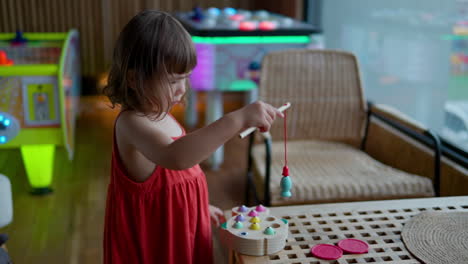 Una-Niña-Adorable-Juega-Un-Juego-De-Pesca-Magnético-En-Un-Café-Interior-Para-Niños