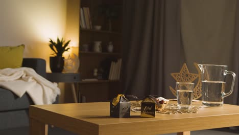 bowl of dates with glass of water and gift boxes on table in muslim home celebrating eid