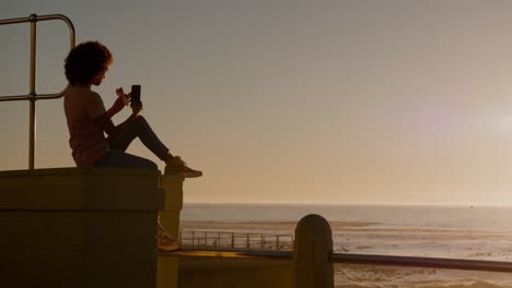 mujer tomando una foto en la playa al atardecer