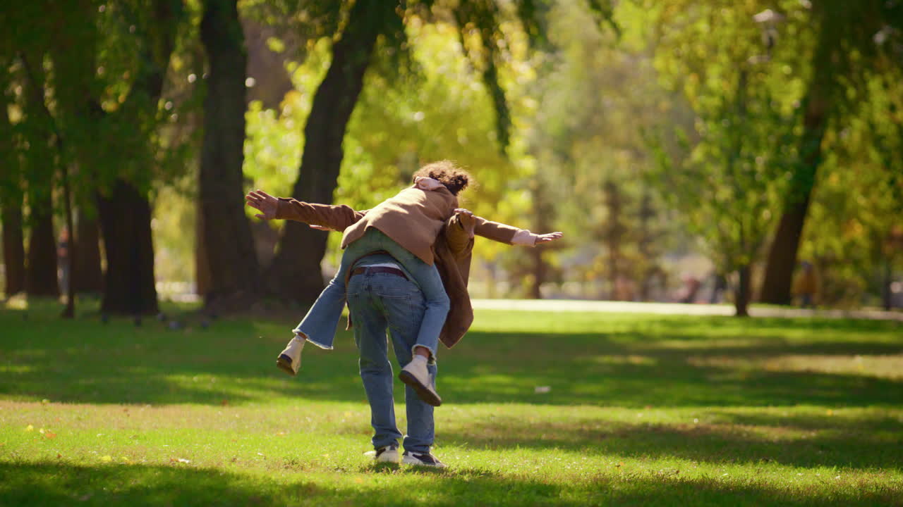 un padre juguetón llevando a su hija disfrutando de un fin de semana en familia en sunny park.