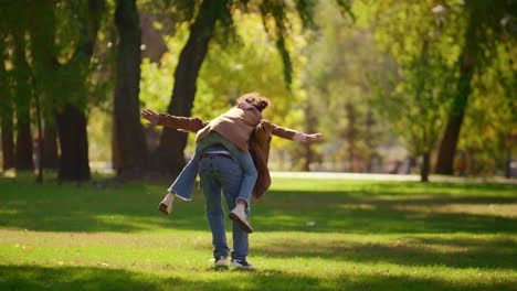 un padre juguetón llevando a su hija disfrutando de un fin de semana en familia en sunny park.