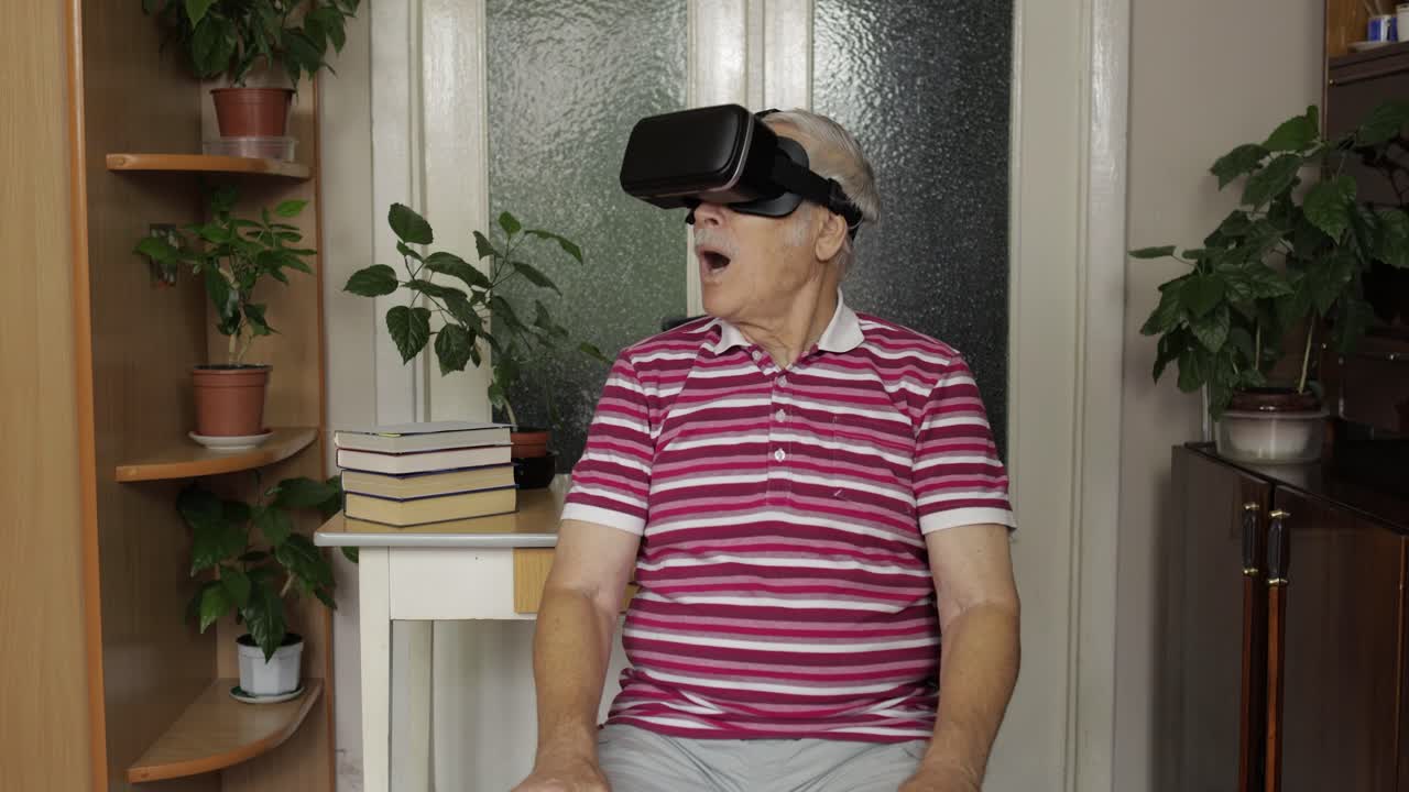 Senior grandfather man in virtual headset glasses watching 3d video in 360 vr helmet at home