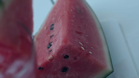 pieza de sandía rosa con semillas se encuentra al lado de vidrio alto