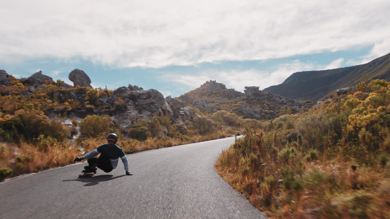 giovane uomo che usa longboard pattinaggio veloce godendo di crociera in discesa su una bellissima strada di campagna a cavallo skateboard rallentamento