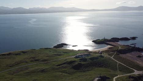 Luftaufnahme-Der-Idyllischen-Insel-Ynys-Llanddwyn-Mit-Der-Dunstigen-Snowdonia-Bergkette-Und-Der-Schimmernden-Irischen-Meereslandschaft