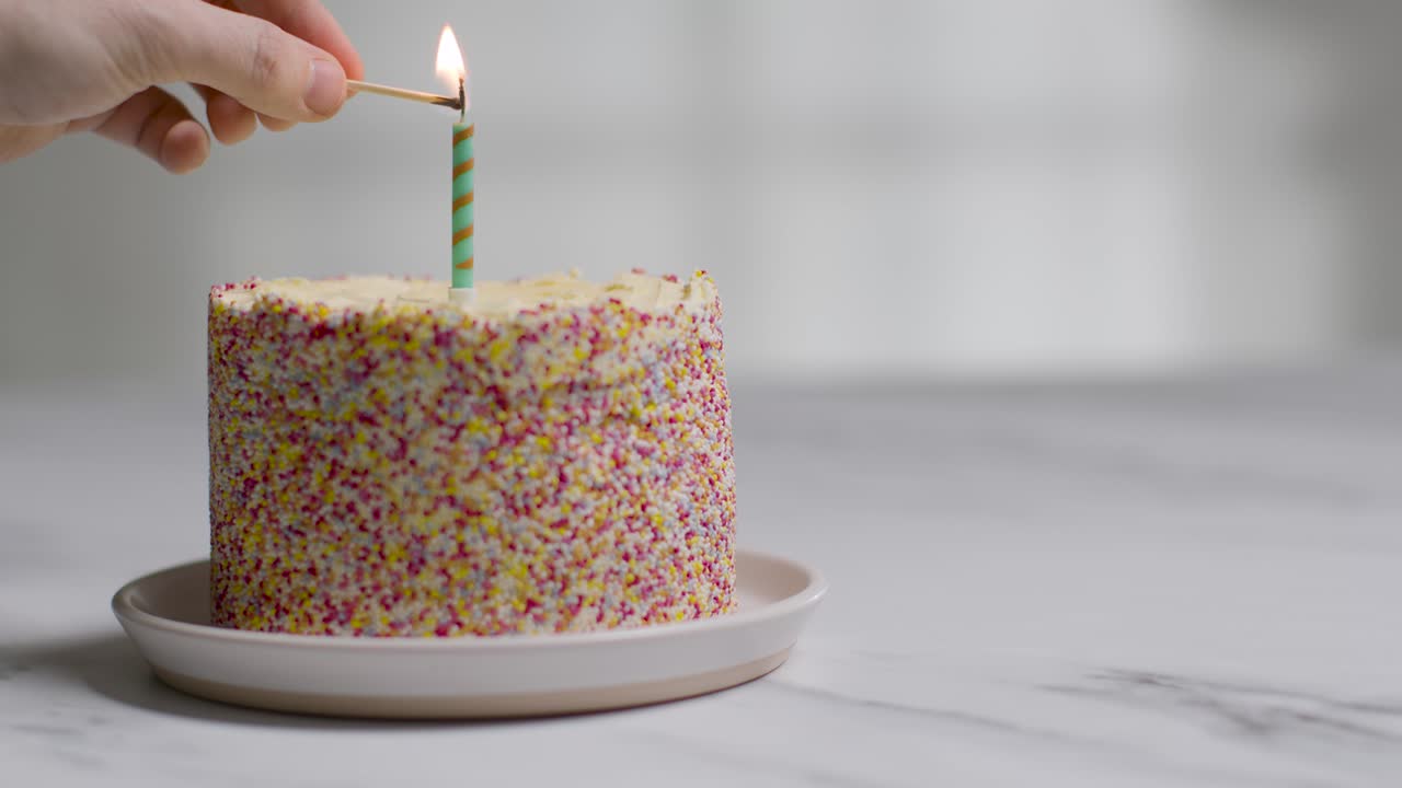 foto de estudio pastel de cumpleaños cubierto con adornos y una sola vela encendida