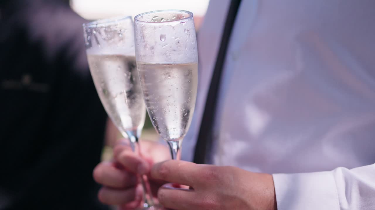 Close-up of two champagne flutes filled with sparkling wine being held together in a celebratory moment