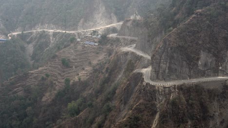 a winding road in the mountains of nepal with a steep cliff on the side as seen from a high angle