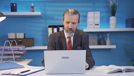 hombre de negocios maduro trabajando en una computadora portátil y regocijándose de su éxito.