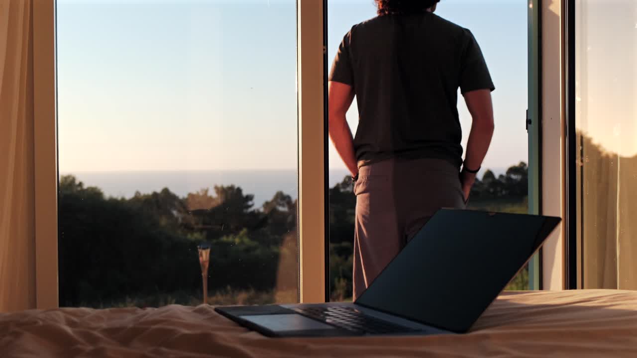 digital nomad taking a break and contemplating ocean on golden hour in slow motion