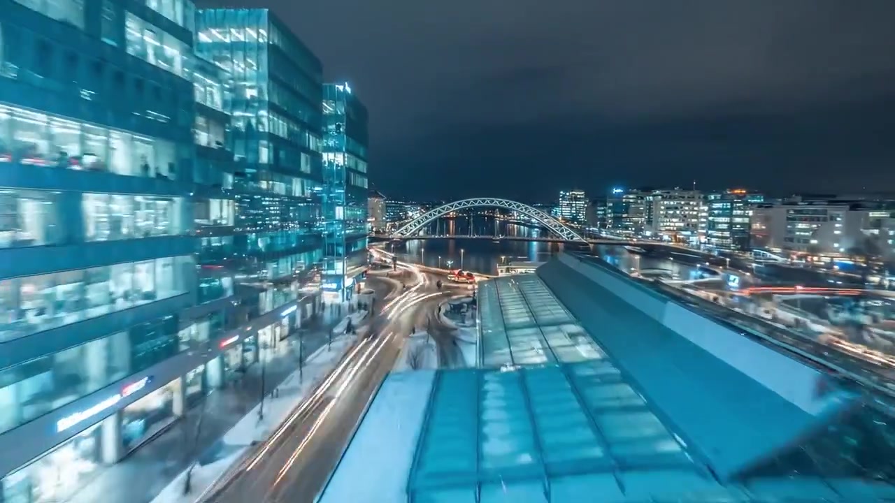 Nighttime urban landscape featuring illuminated buildings, busy streets, and vibrant traffic in a metropolitan area, highlighting modern architecture and city life.