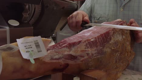 man slicing typical jamon iberico leg of ham with sharp knife in spain