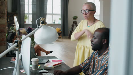 Multiethnic-Colleagues-Working-on-Computer-and-Talking-in-Office