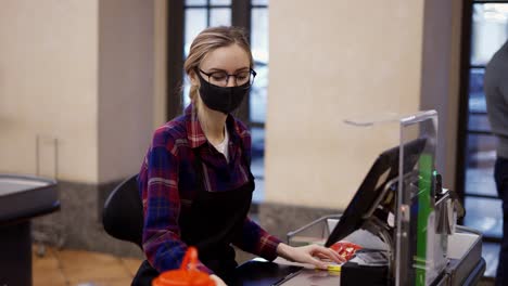 female cashier in a protective mask and gloves pierces the products with the scanner