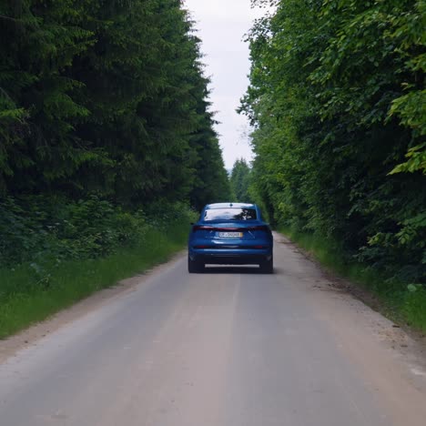 test drive audi on a road among green trees. modern electronic car model moving on a highway. blue e-tron car model. luxury electric car for saving ecology